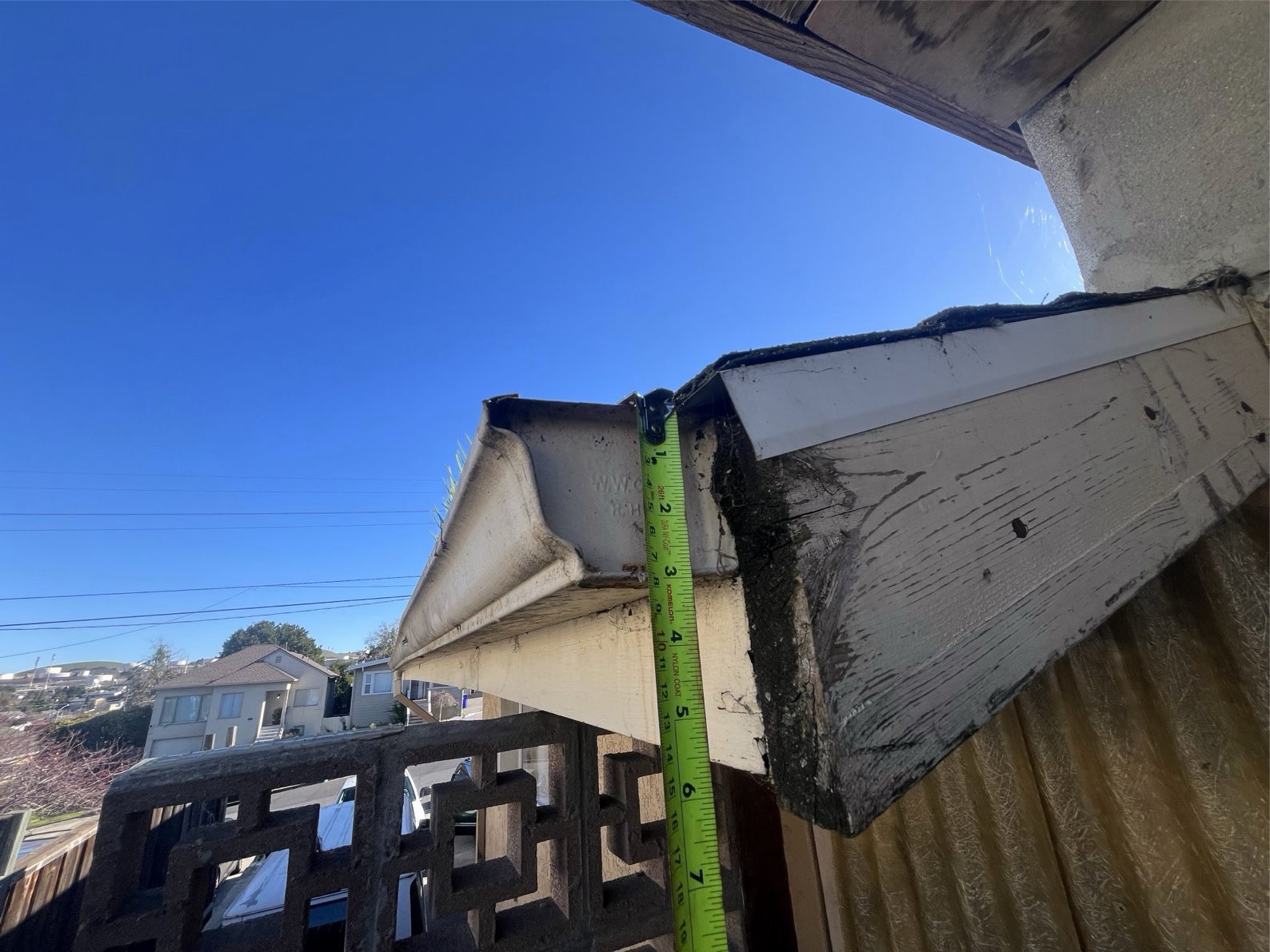A tape measure documenting the depth of fascia board rot exposed when the gutter was pulled away from the house — the clearest fascia damage finding in the inspection library