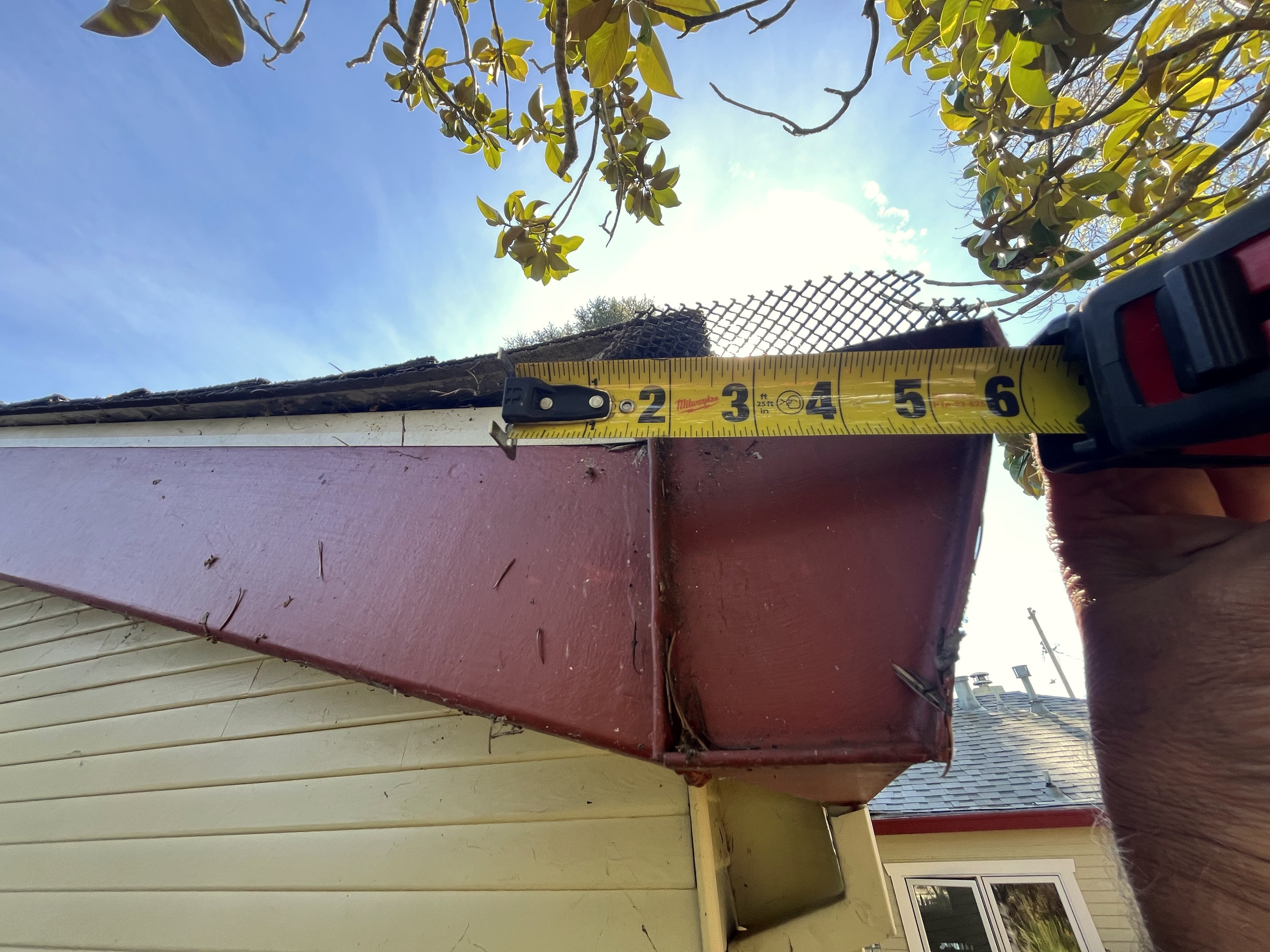 Micro-mesh gutter guard with measurement tape documenting penetration depth where mesh meets aluminum gutter — Northern California field inspection.